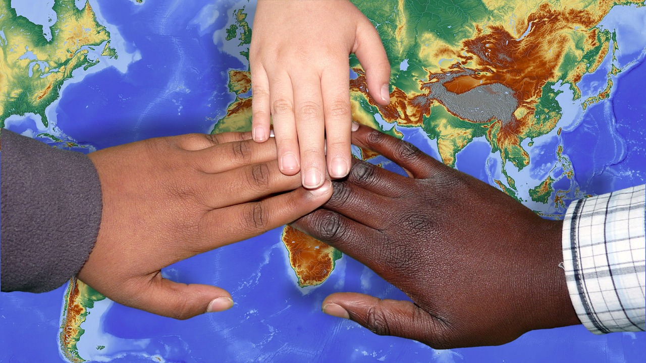 Weltkarte auf drei Händen liegen. Alle drei Hände haben eine unterschiedliche Hautfarbe.